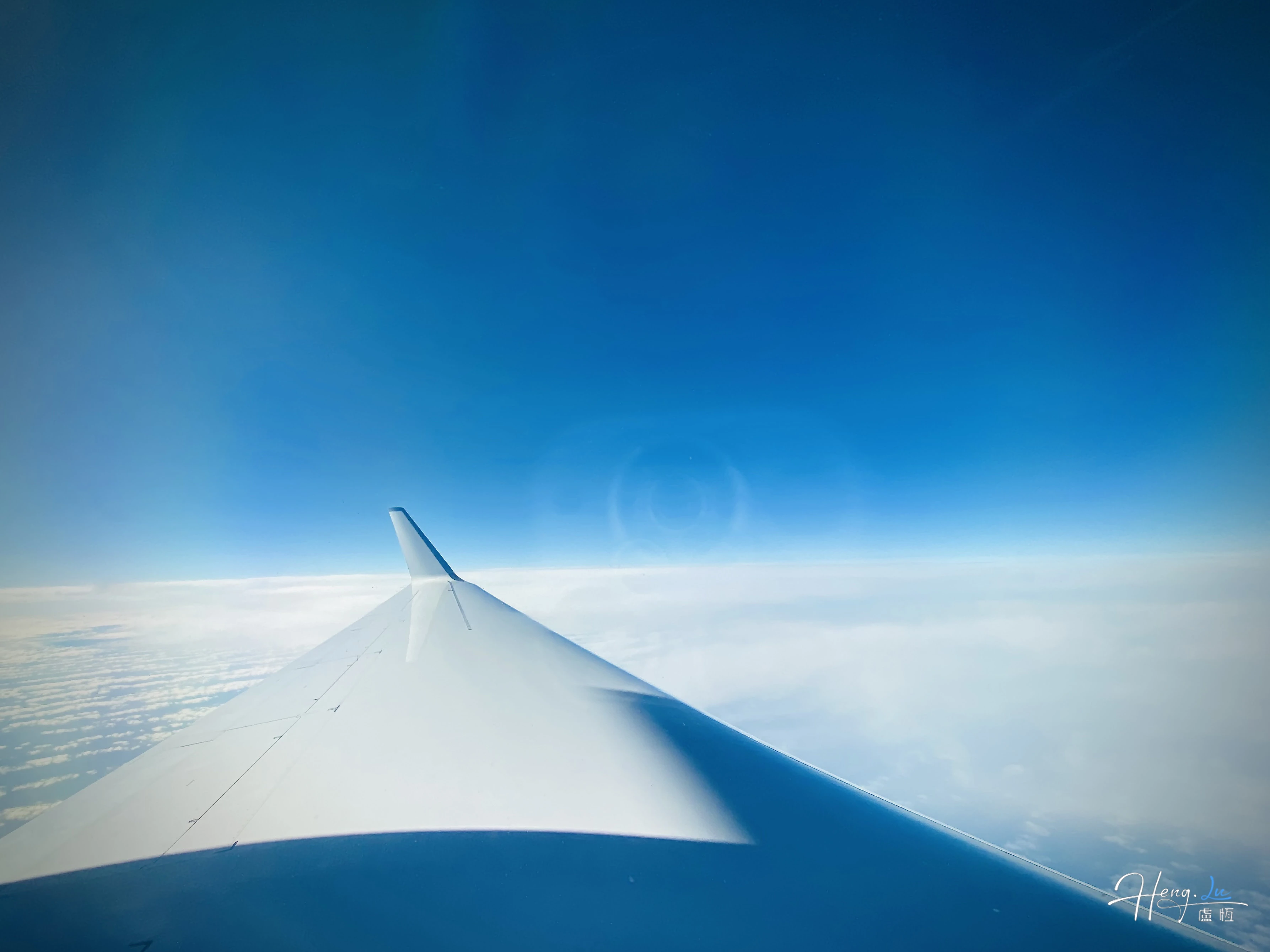 Airplane wing above clouds by Heng Lu